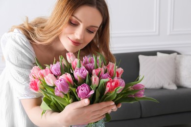 Young woman with bouquet of beautiful tulips indoors