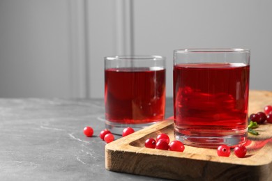 Photo of Tasty refreshing cranberry juice and fresh berries on grey textured table. Space for text
