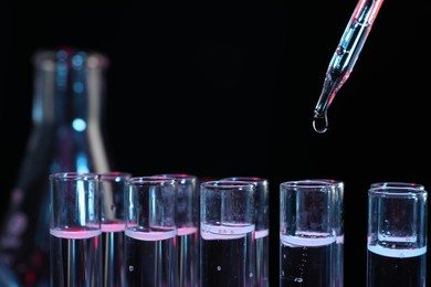 Photo of Dripping reagent into test tube on black background, closeup. Laboratory analysis