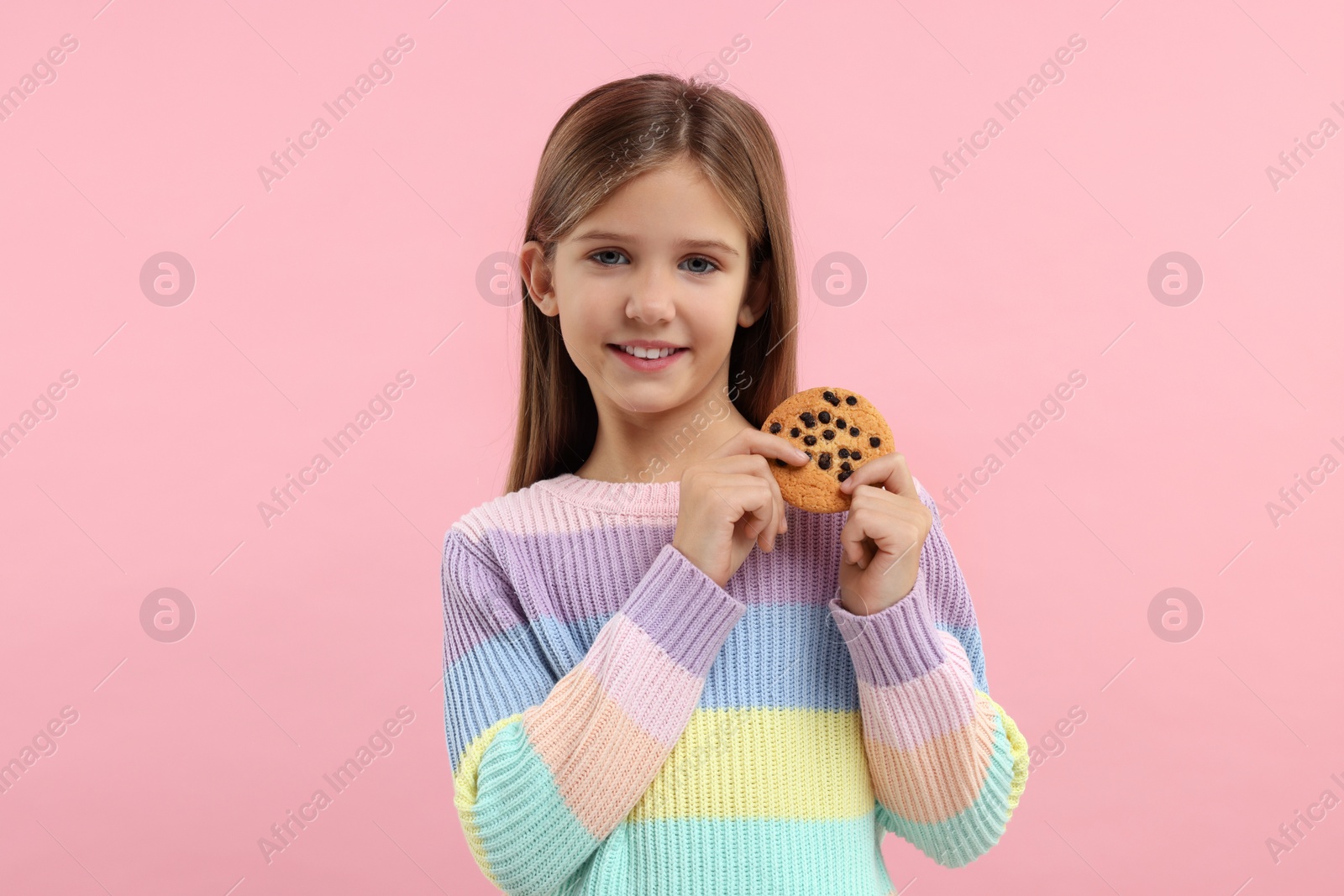 Photo of Cute girl with chocolate chip cookie on pink background