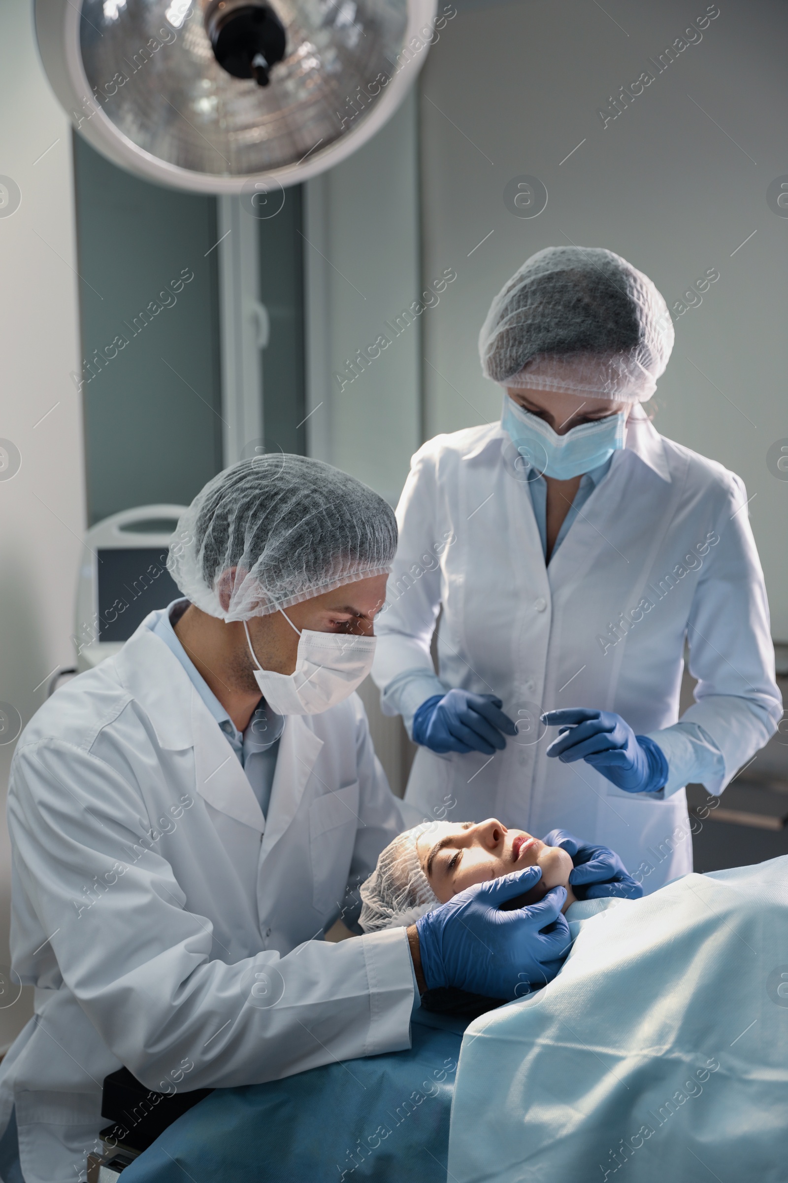 Photo of Doctor and nurse preparing female patient for cosmetic surgery in clinic