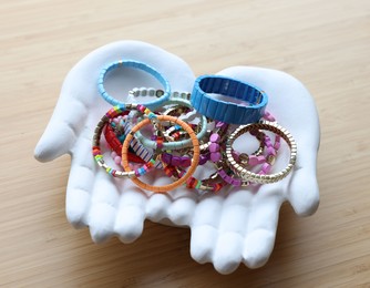 Photo of Ceramic hand stand with many stylish bracelets on wooden table