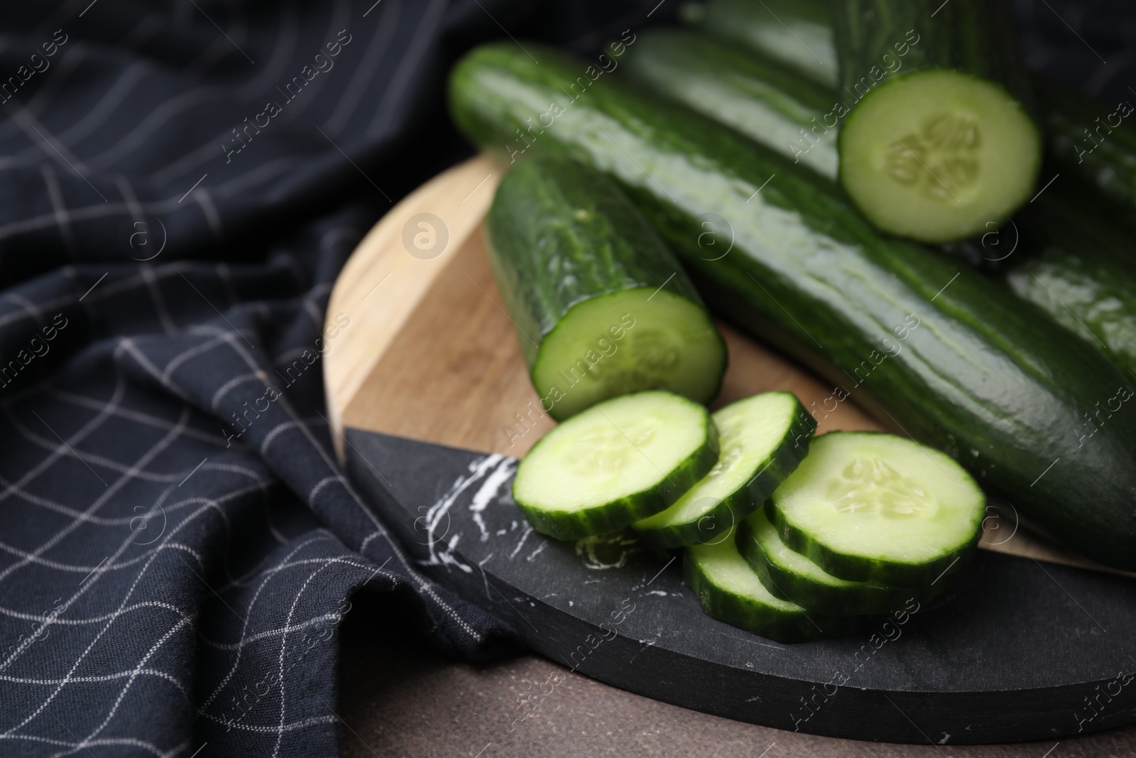 Photo of Fresh whole and cut cucumbers on table, closeup