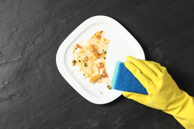 Photo of Woman washing dirty plate at black table, top view