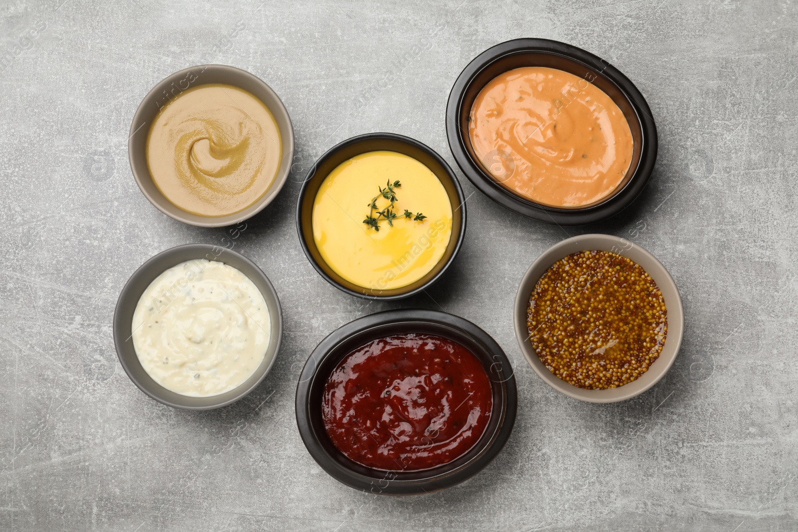 Photo of Many different sauces on grey table, flat lay