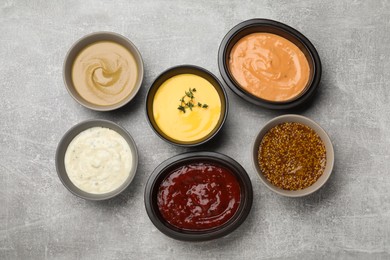 Photo of Many different sauces on grey table, flat lay