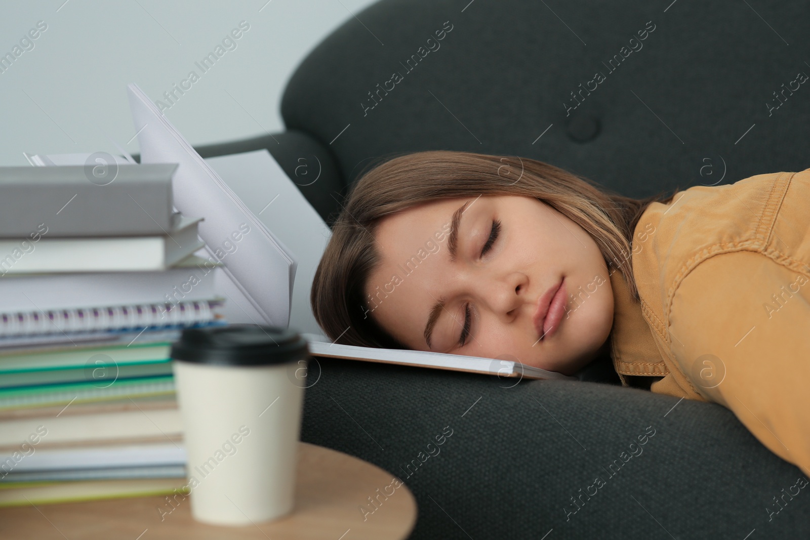Photo of Young tired woman sleeping near books on couch indoors, closeup