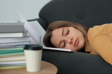 Young tired woman sleeping near books on couch indoors, closeup