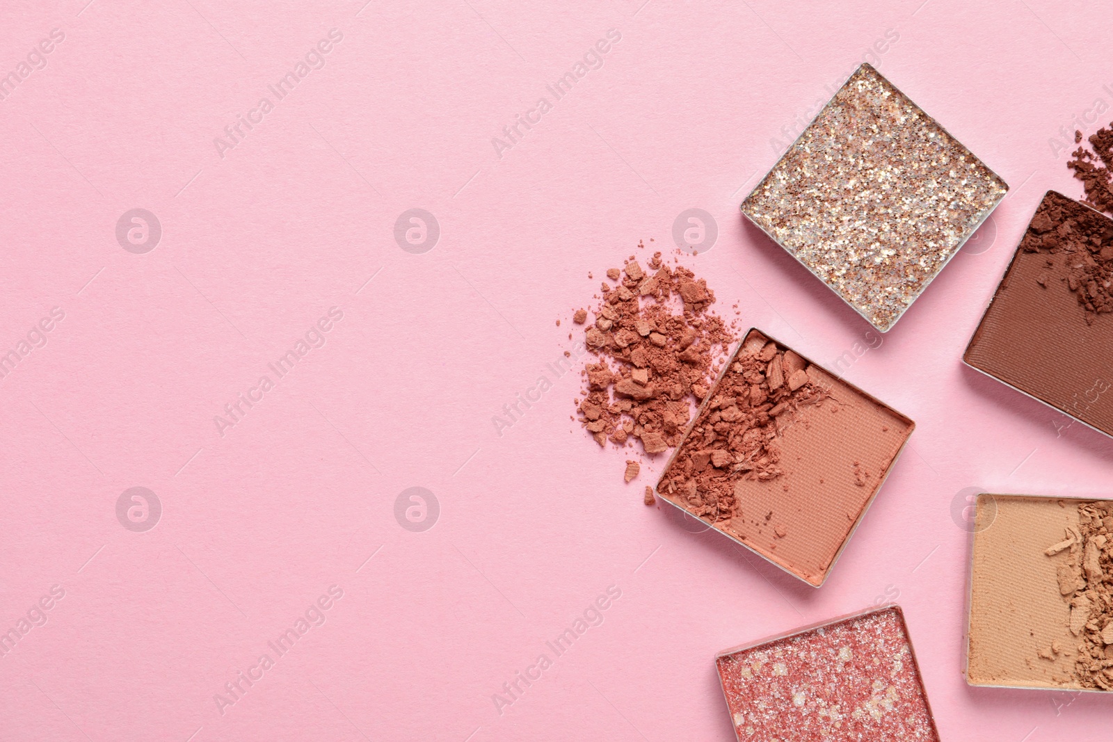 Photo of Crushed eye shadows on pink background, flat lay with space for text. Professional makeup product