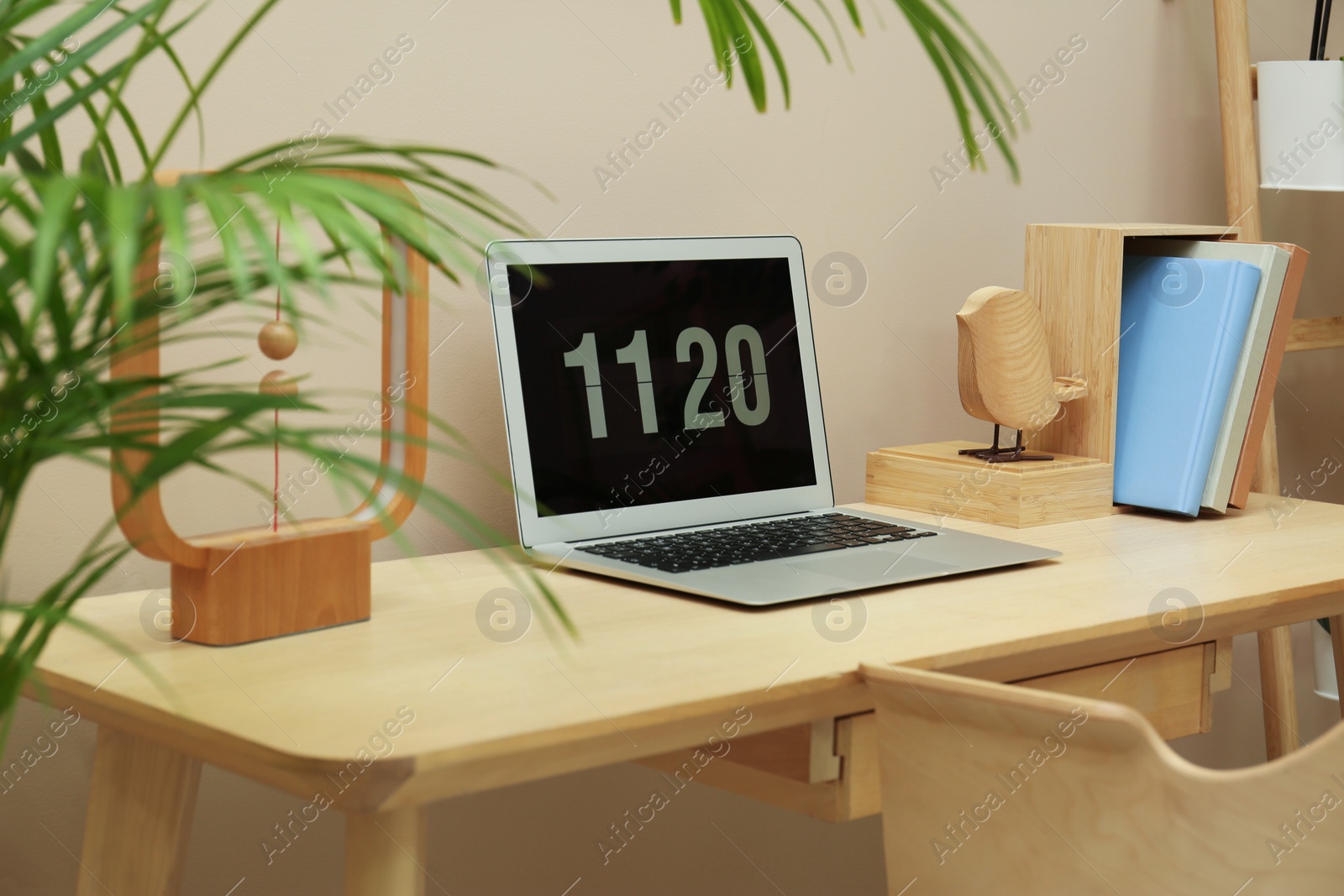 Photo of Stylish workplace with laptop, notebooks and houseplant indoors. Interior design