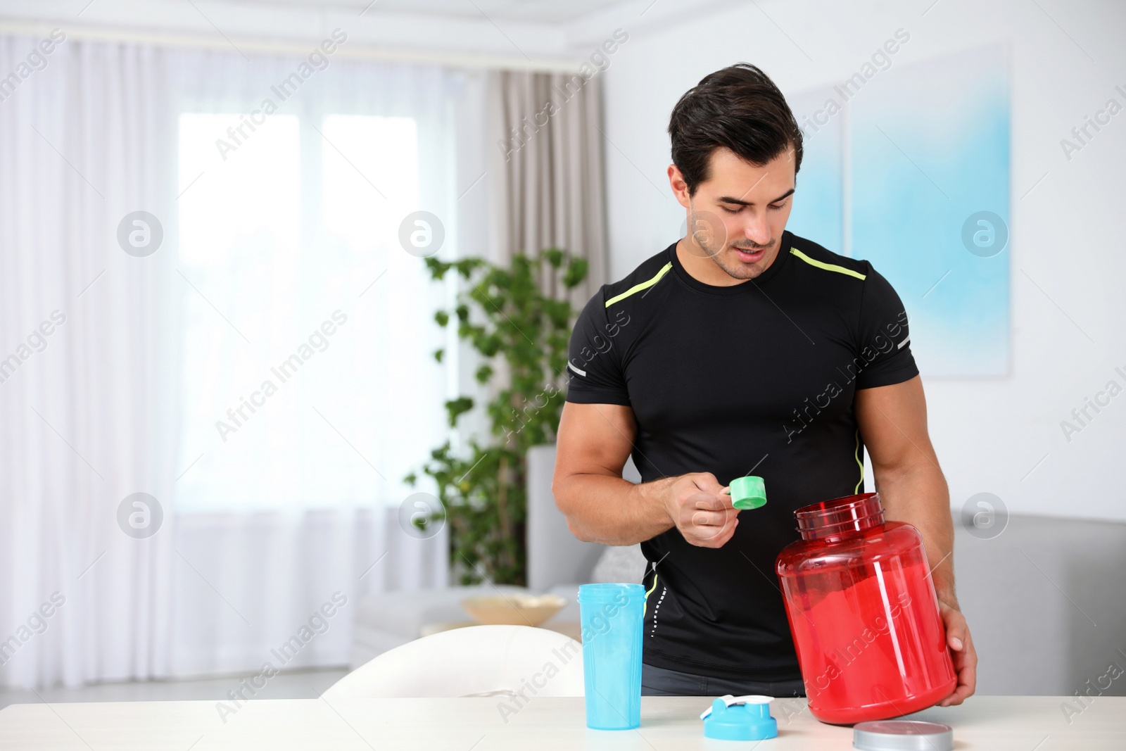Photo of Young athletic man preparing protein shake at home, space for text