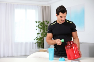 Young athletic man preparing protein shake at home, space for text