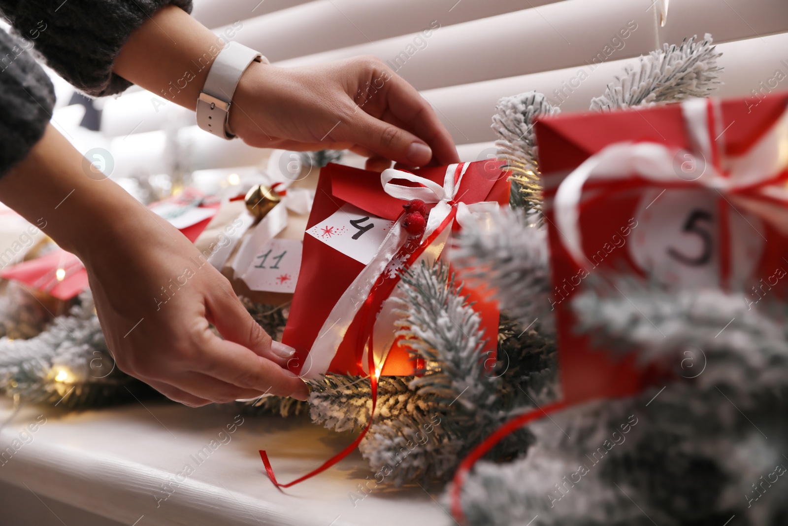 Photo of Woman making Christmas advent calendar, focus on paper bag with gift