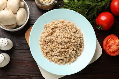 Photo of Delicious pearl barley served on wooden table, flat lay