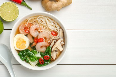 Photo of Tasty ramen with shrimps in bowl on white wooden table, flat lay. Space for text