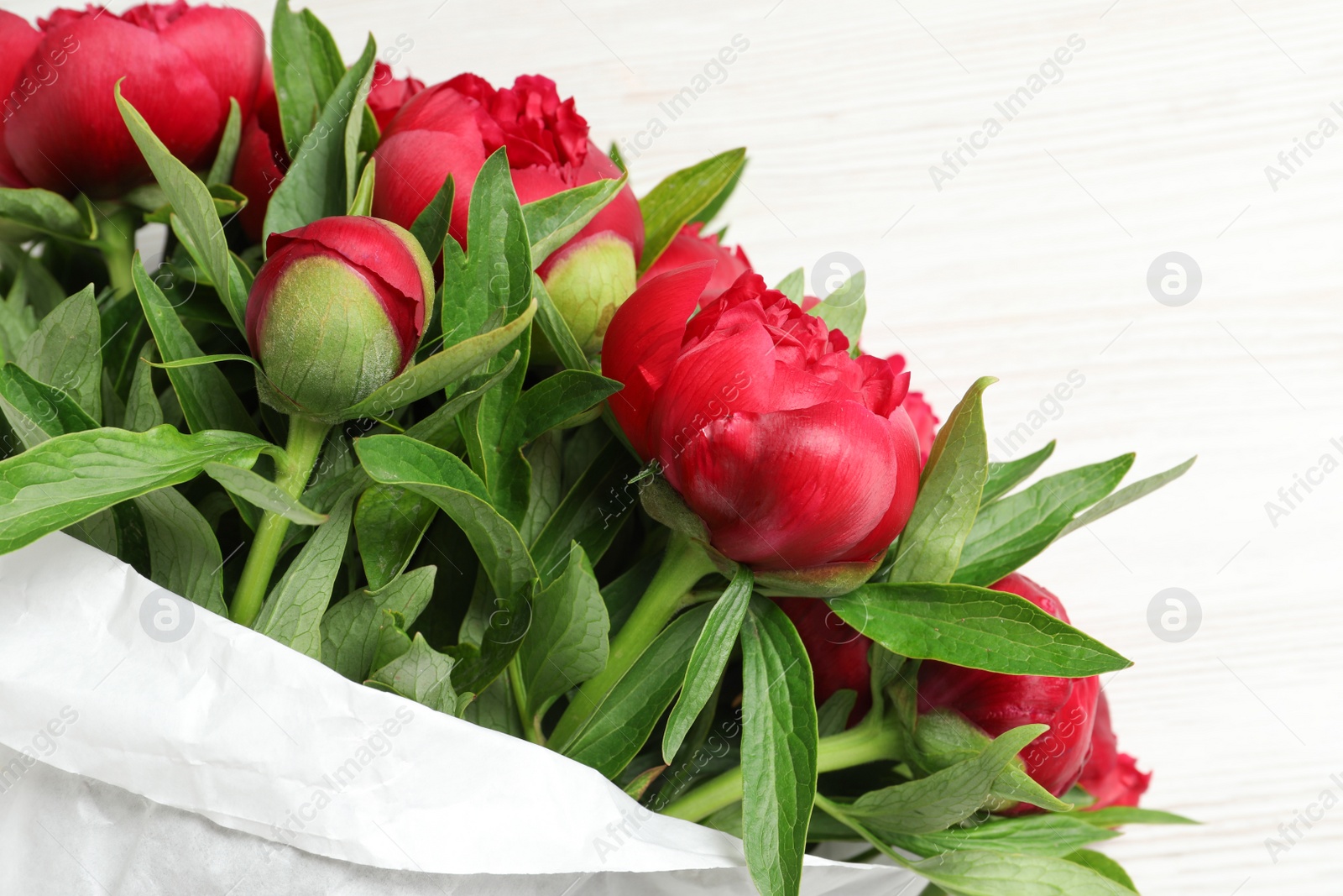 Photo of Beautiful bouquet of red peony flowers on white table, closeup