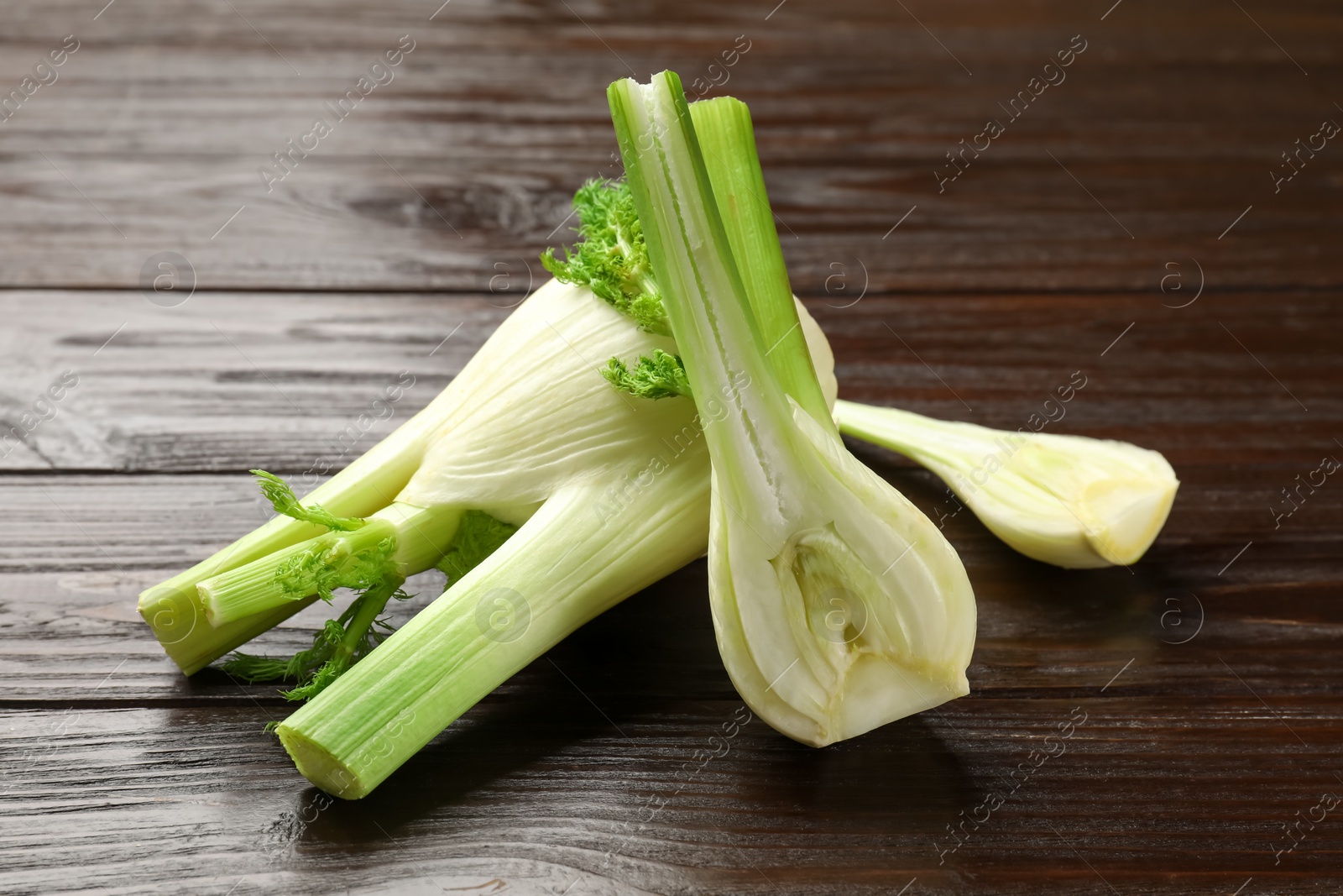 Photo of Whole and cut fennel bulbs on wooden table, closeup