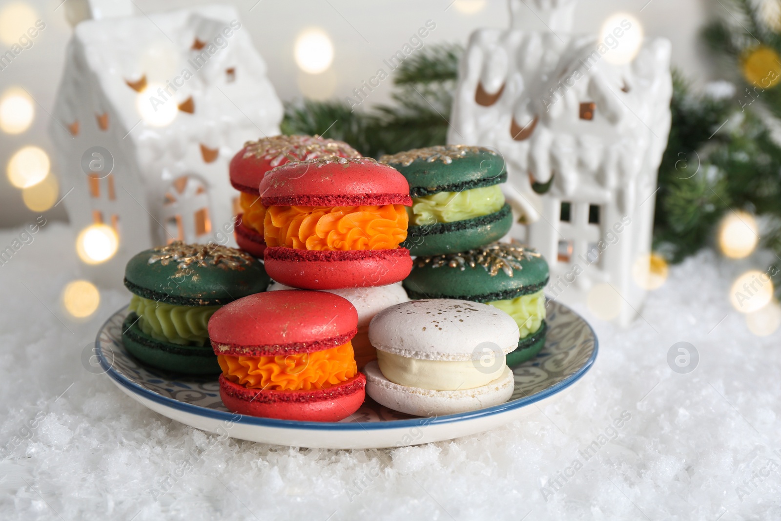 Photo of Different decorated Christmas macarons on table with artificial snow