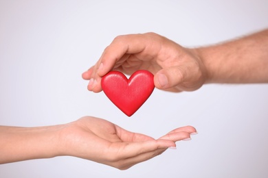 Photo of Man giving red heart to woman on white background, closeup. Donation concept