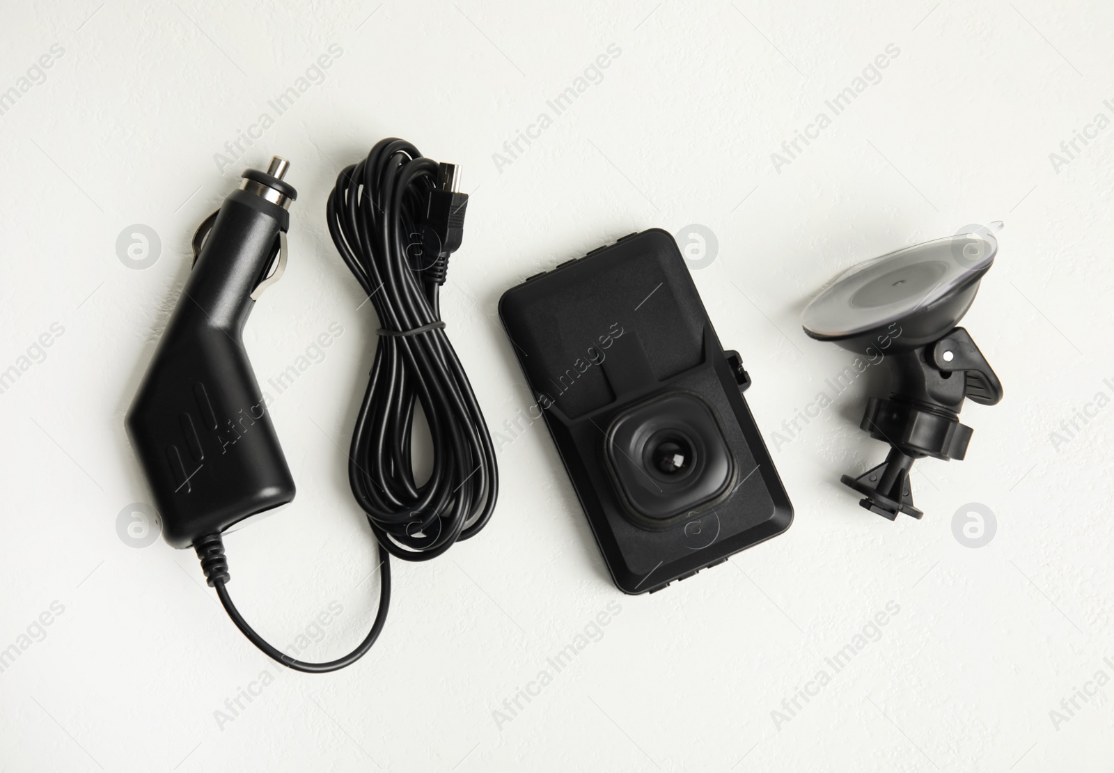 Photo of Modern car dashboard camera, suction mount and charger on white background, flat lay