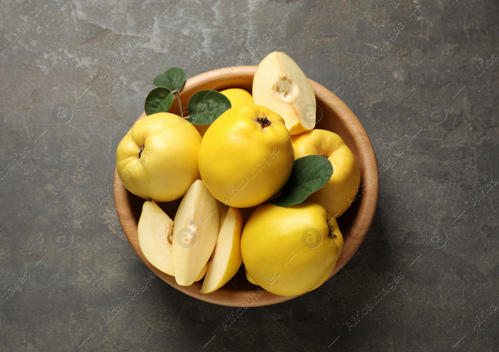 Photo of Fresh ripe organic quinces with leaves on grey table, top view