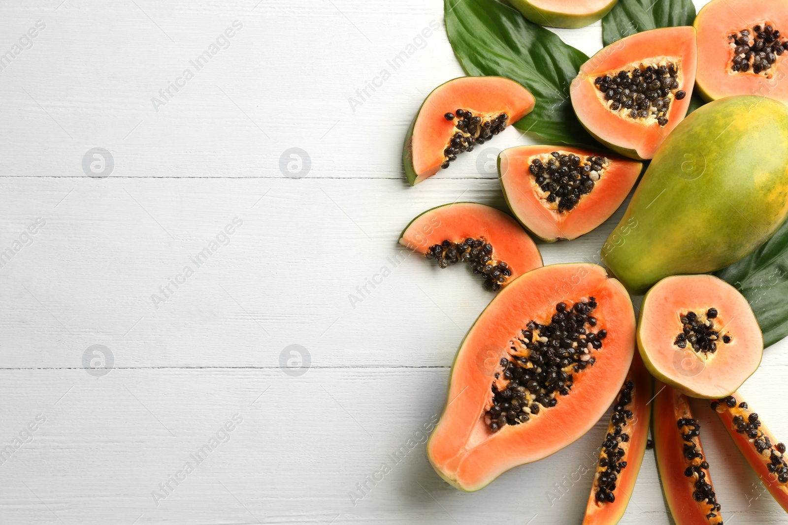 Photo of Fresh ripe papaya fruits on white wooden table, flat lay. Space for text