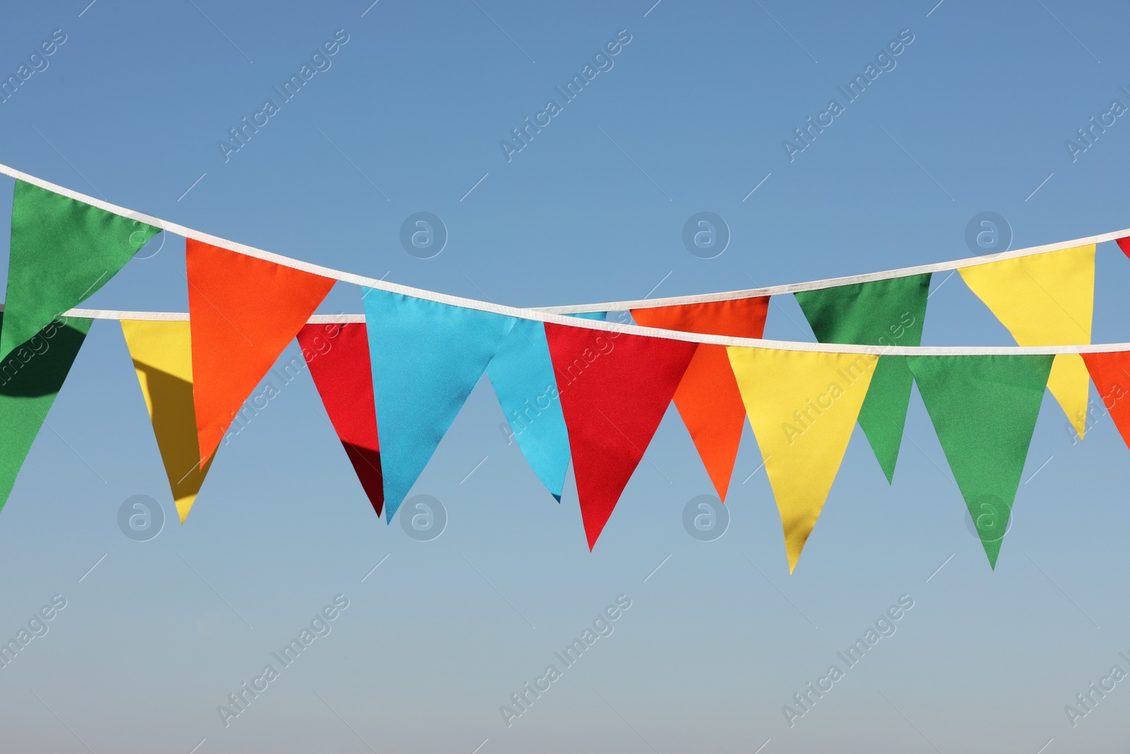 Photo of Buntings with colorful triangular flags against blue sky