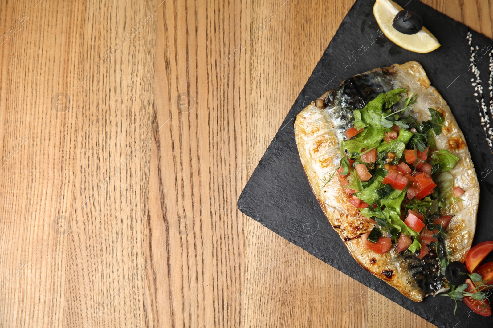 Photo of Delicious grilled fish served on wooden table, top view. Space for text