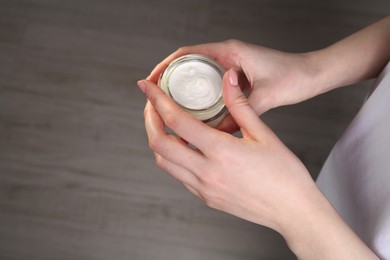 Woman applying hand cream indoors, above view