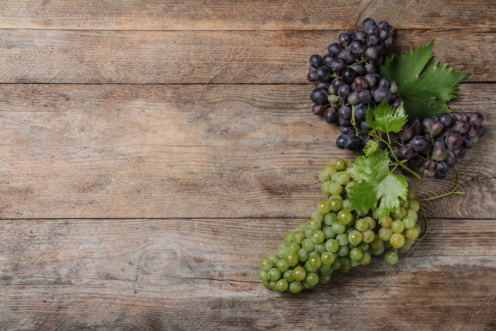 Photo of Flat lay composition with fresh ripe juicy grapes on wooden table, space for text