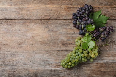 Flat lay composition with fresh ripe juicy grapes on wooden table, space for text