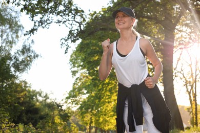 Woman running outdoors in morning, low angle view. Space for text