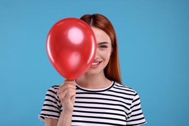 Photo of Happy woman with red balloon on light blue background