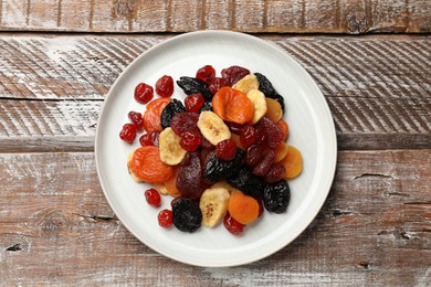 Photo of Mix of delicious dried fruits on wooden table, top view