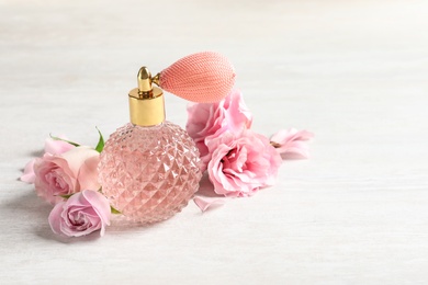 Photo of Vintage bottle of perfume and flowers on light stone background, space for text