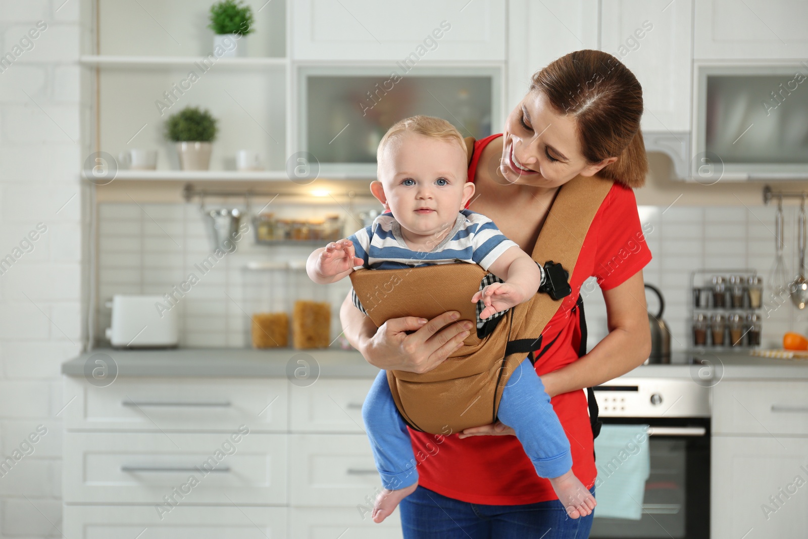 Photo of Woman with her son in baby carrier at home. Space for text