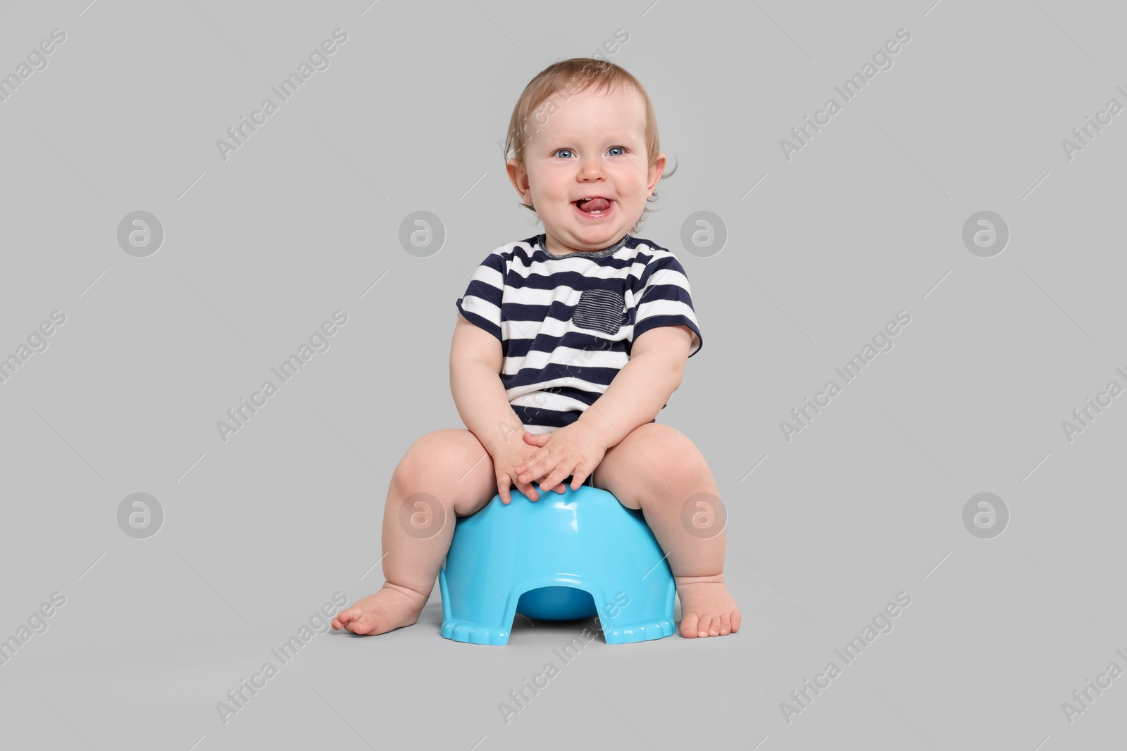 Photo of Little child sitting on baby potty against light grey background