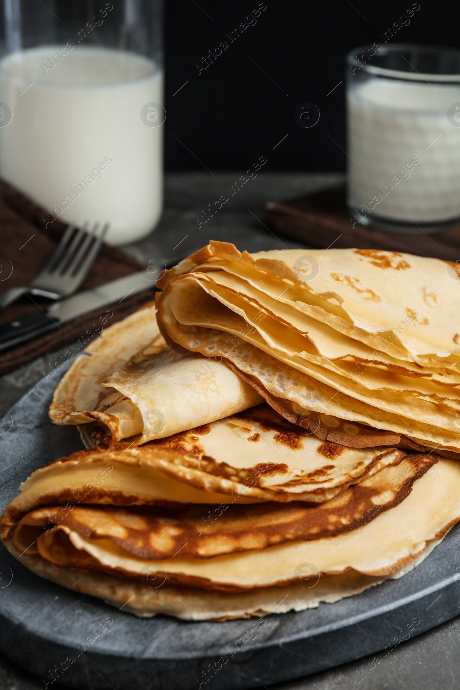 Photo of Fresh thin pancakes on grey board, closeup