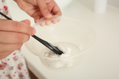 Photo of Woman preparing hair dye in bowl at home, closeup