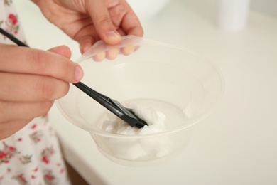 Woman preparing hair dye in bowl at home, closeup