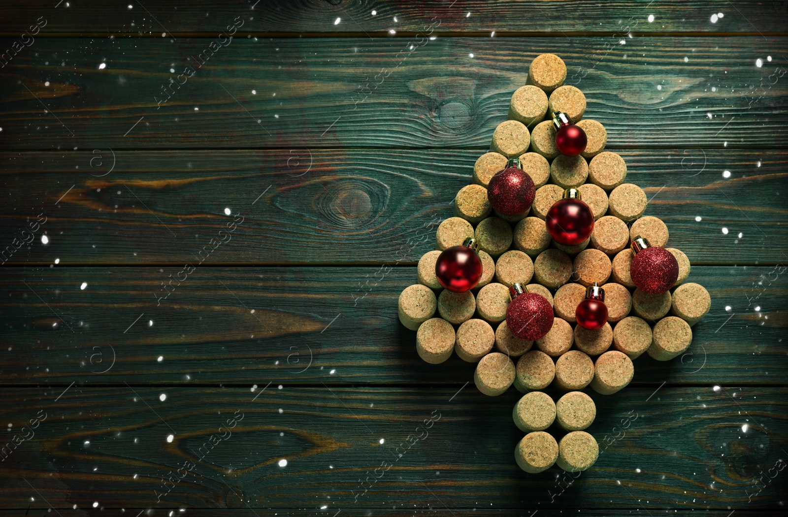 Image of Christmas tree made of wine corks and red baubles on green wooden table, top view. Space for text