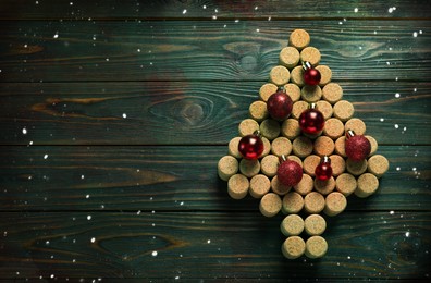 Christmas tree made of wine corks and red baubles on green wooden table, top view. Space for text
