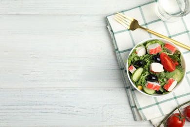 Photo of Tasty crab stick salad served on white wooden table, flat lay. Space for text