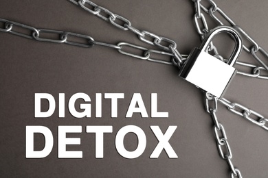 Image of Digital detox concept. Steel padlock, chains and text on grey background, flat lay