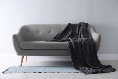 Photo of Soft knitted blanket on sofa in room. Home interior