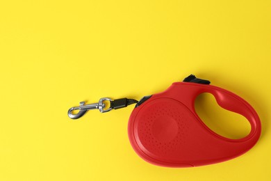 Red dog retractable leash on yellow background, top view. Space for text