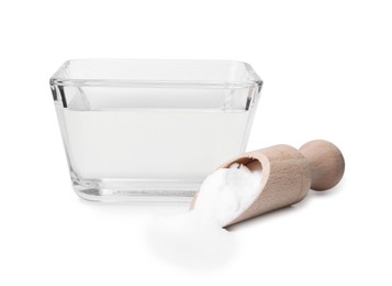 Vinegar in glass bowl, baking soda and wooden scoop isolated on white