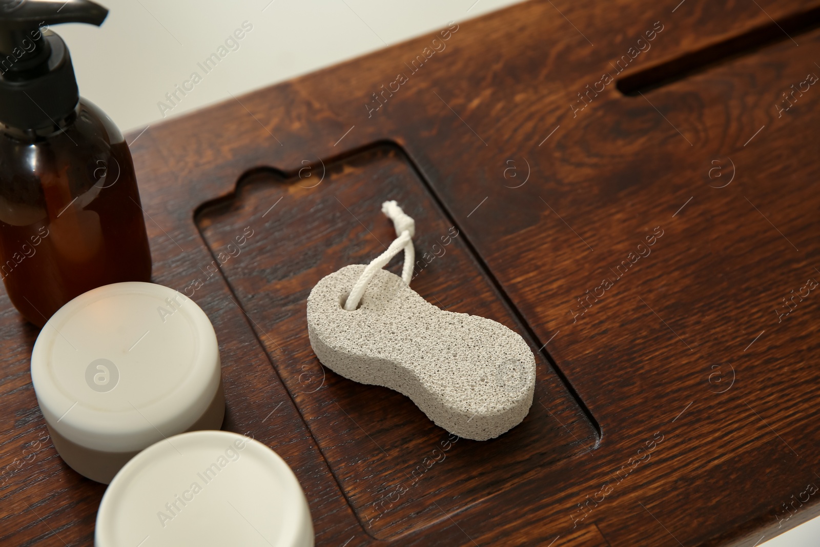 Photo of Pumice stone and cosmetic products on wooden tray, closeup. Space for text