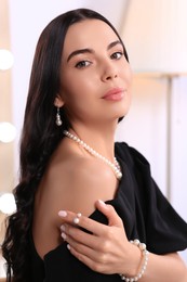 Young woman wearing elegant pearl jewelry indoors