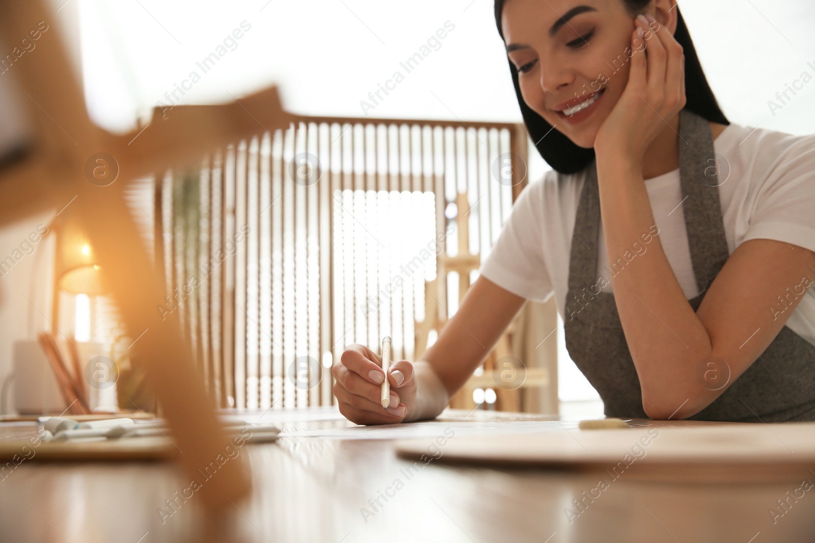 Photo of Young woman drawing with pencil at table indoors